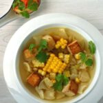 Miska pożywnej zupy warzywnej, z kukurydzą, makaronem i tofu.