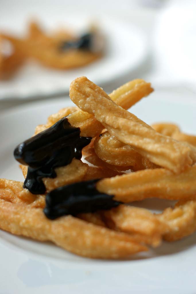 chrupiące, złote hiszpańskie churros, ciastka smażone z cukrem pudrem i sosem czekoladowym