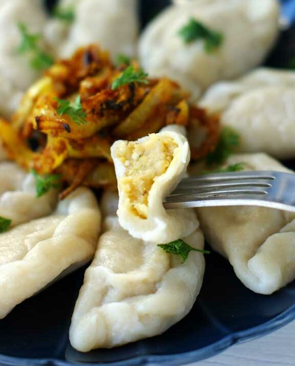 Ugotowane pierogi z soczewicą podane z prażoną cebulką.