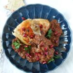 Pieczony, złocisty kurczak w kawałkach z sosem czekoladowym i granatem. Miniaturka.