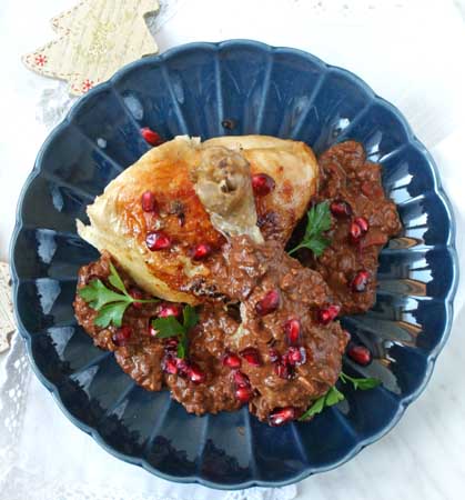 Pieczony, złocisty kurczak w kawałkach z sosem czekoladowym i granatem. Miniaturka.