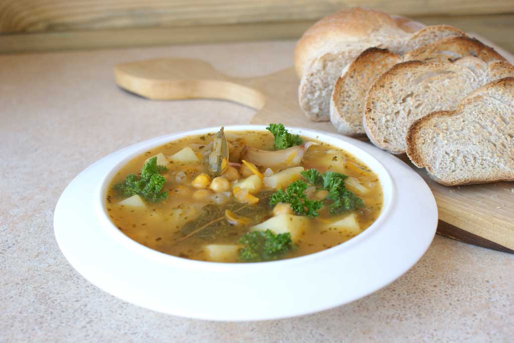 porcja zupy z ciecierzycy, z zieleniną i tostami