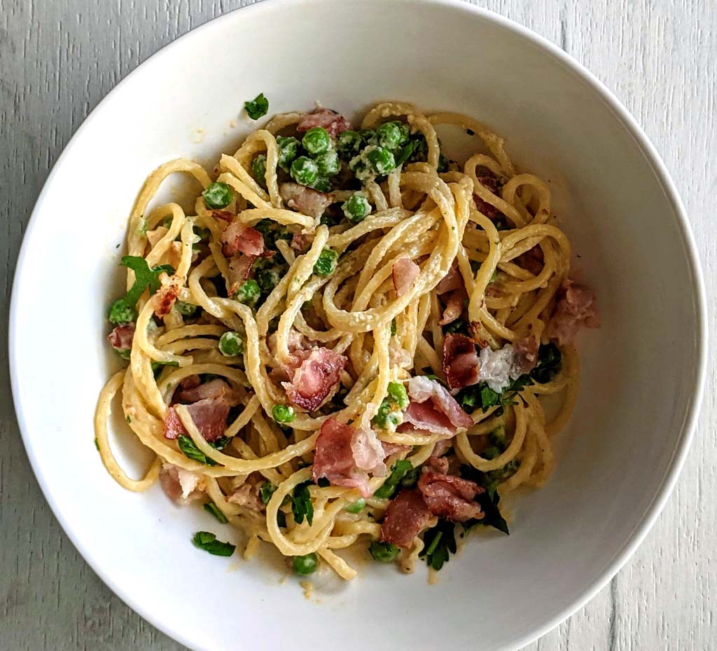 Porcja energetycznego spaghetti alla carbonara z kawałkami boczku.