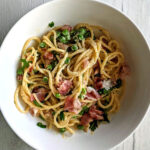 Porcja energetycznego spaghetti alla carbonara z kawałkami boczku.