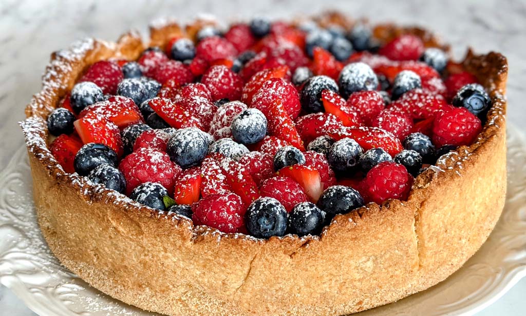 Smakowita tarta z aksamitnym kremem budyniowym i owocami jagodowymi.