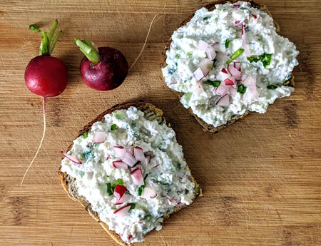 Kromki żytniego chleba z pastą z twarogu i nowalijek.